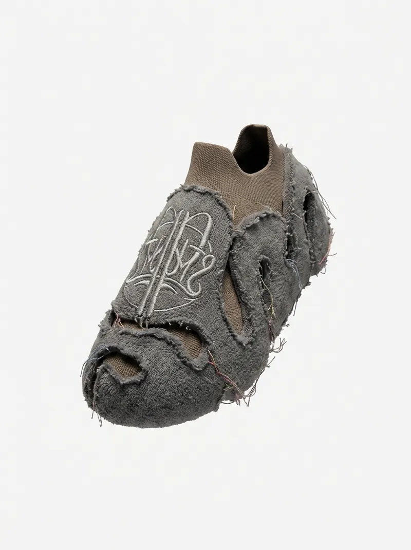 A single grey slip-on shoe with a fuzzy outer layer, cut-outs and a light logo on top, shown at an angle on a light grey background.
